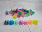 Load image into Gallery viewer, Rainbow bright coloured bobbin colours. Clear plastic, universal fit. Orange, pink, yellow, red, purple, green, blue and black bobbin
