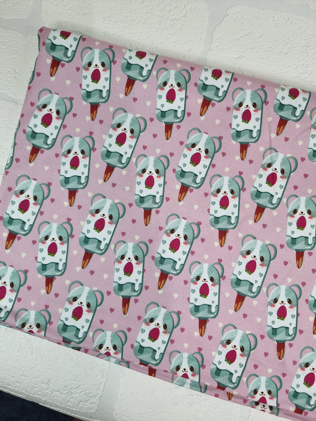 Adorable puppies on popsicle sticks on a pale pink background on bamboo lycra fabric.