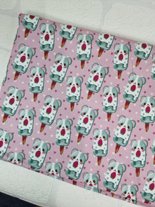 Adorable puppies on popsicle sticks on a pale pink background on bamboo lycra fabric.