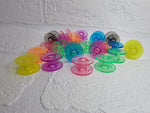 Load image into Gallery viewer, Rainbow bright coloured bobbin colours. Clear plastic, universal fit. Orange, pink, yellow, red, purple, green, blue and black bobbin
